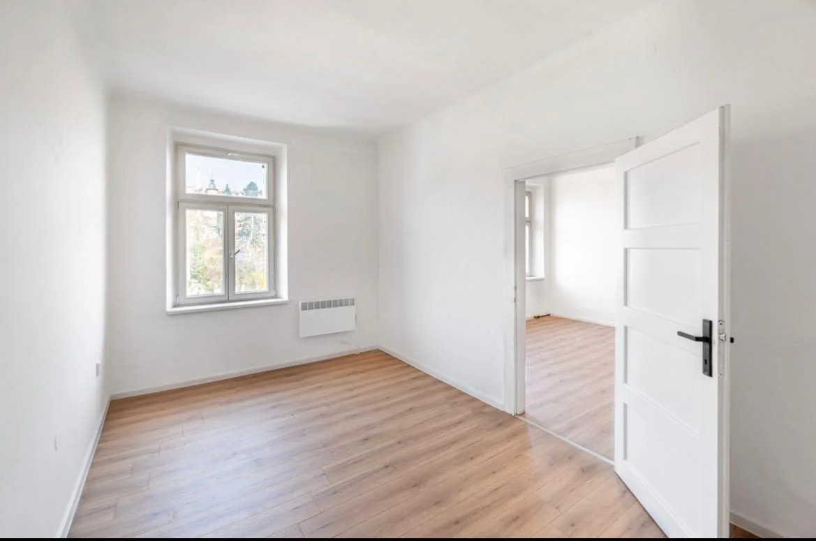 Prázdný pokoj po kompletní výmalbě do bílé barvy s bílými dveřmi a okny.