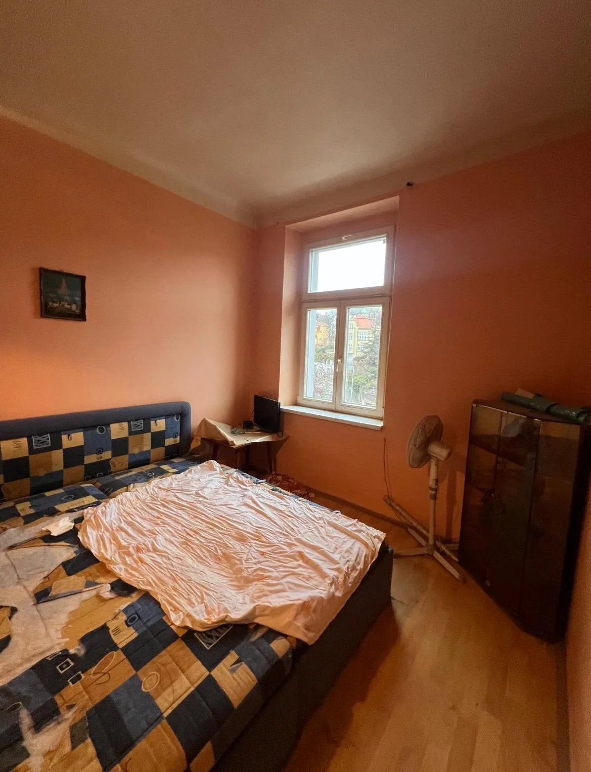 Ložnice se sytě oranžovými stěnami před přemalováním.