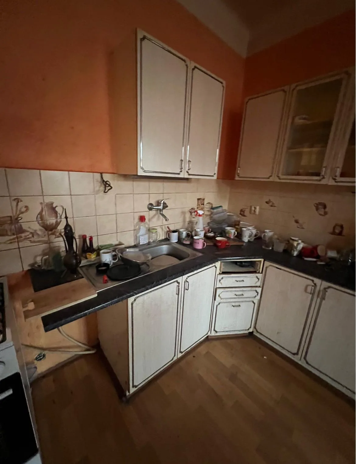 Starší kuchyň s oranžovou stěnou před rekonstrukcí a malováním.