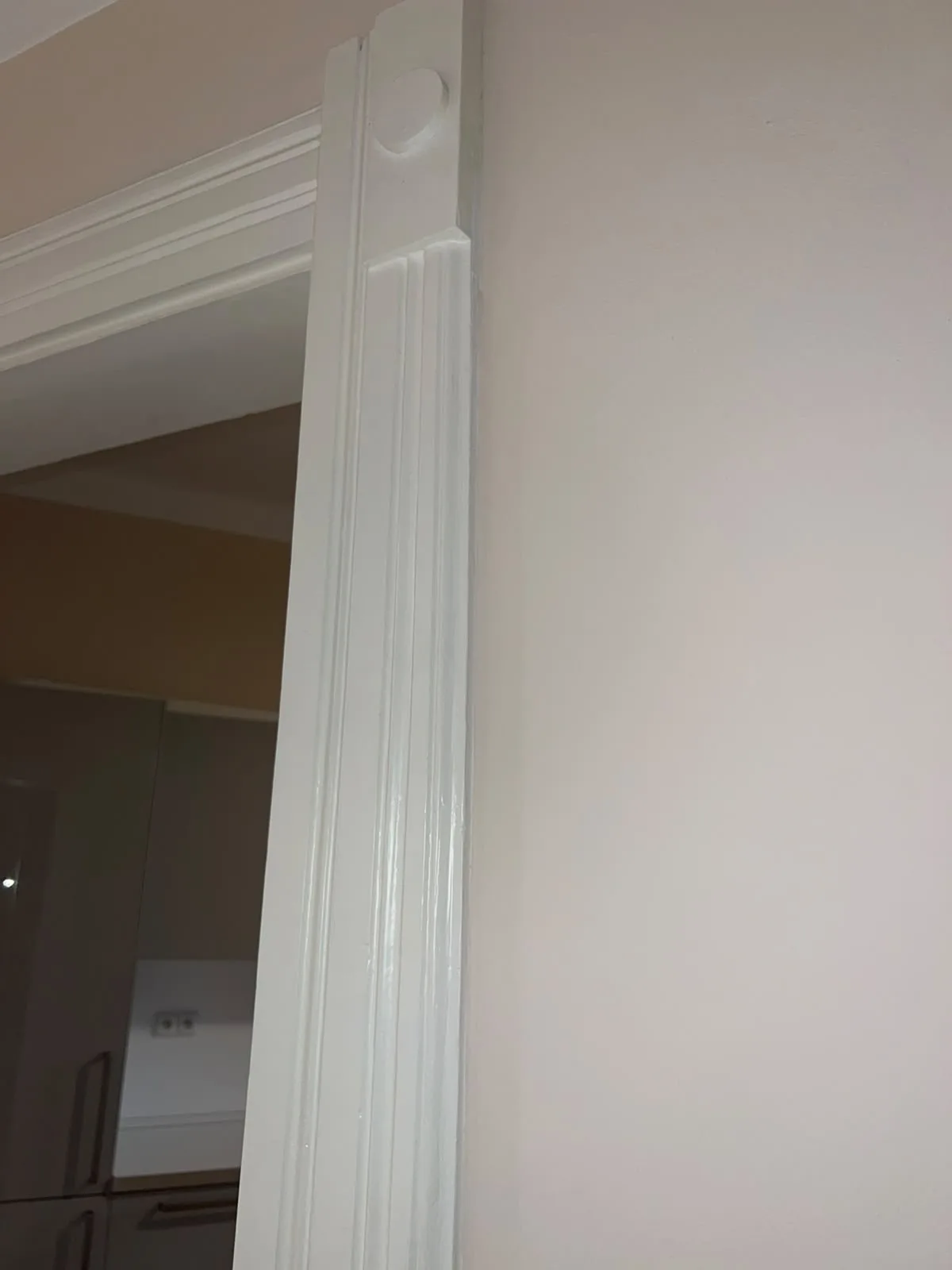 Detail bíle natřené profilované dřevěné zárubně dveří.