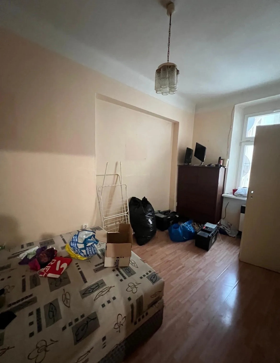 Pokoj se světle broskvovými stěnami při vyklízení před malováním.