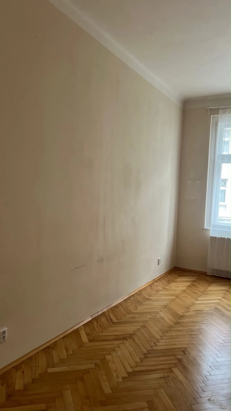 Prázdný pokoj s béžovými stěnami před malováním.