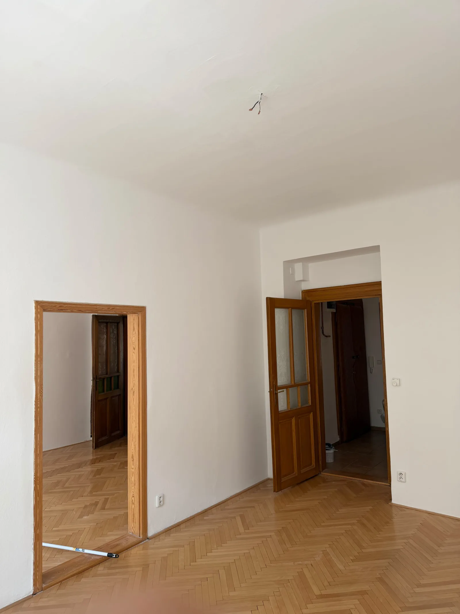 Vymalovaný pokoj s bílými stěnami a dřevěnými dveřmi.