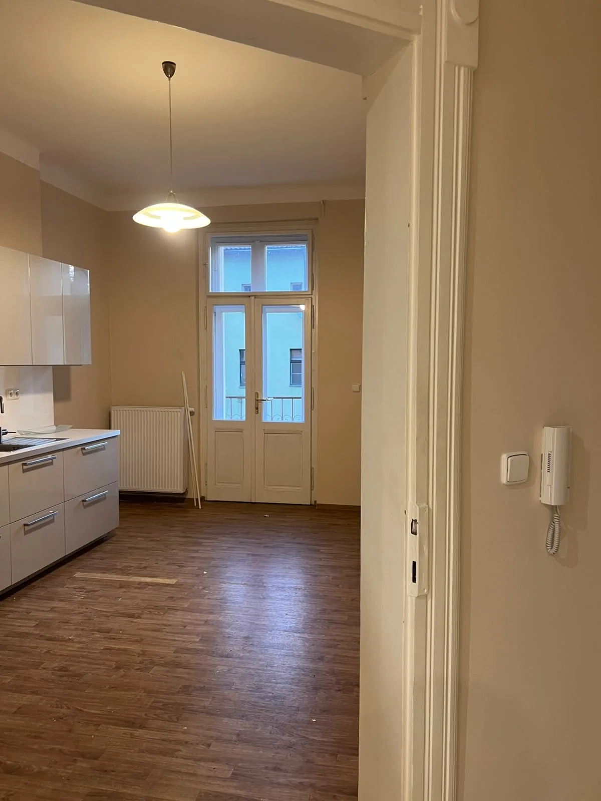 Vymalovaný prázdný byt v teplém béžovém odstínu s kuchyňskou linkou.