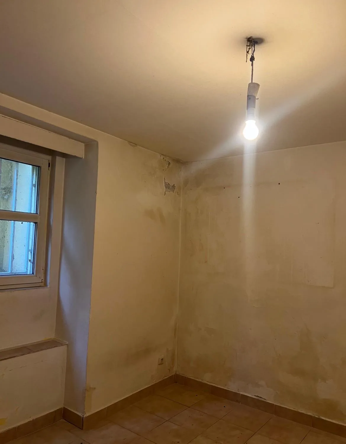 Místnost před opravou s poškozenou omítkou stěn.