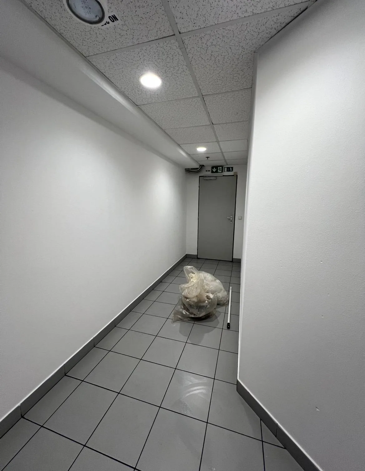 Vymalovaná chodba komerčního prostoru se šedou dlažbou.