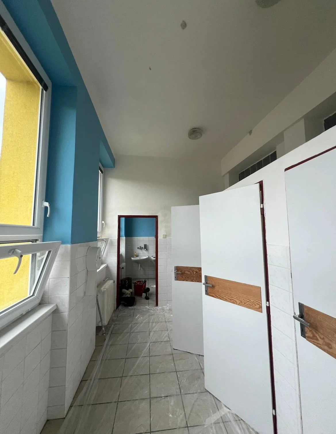 Sociální zařízení během malování s modro-bílou výmalbou a zakrytou podlahou.