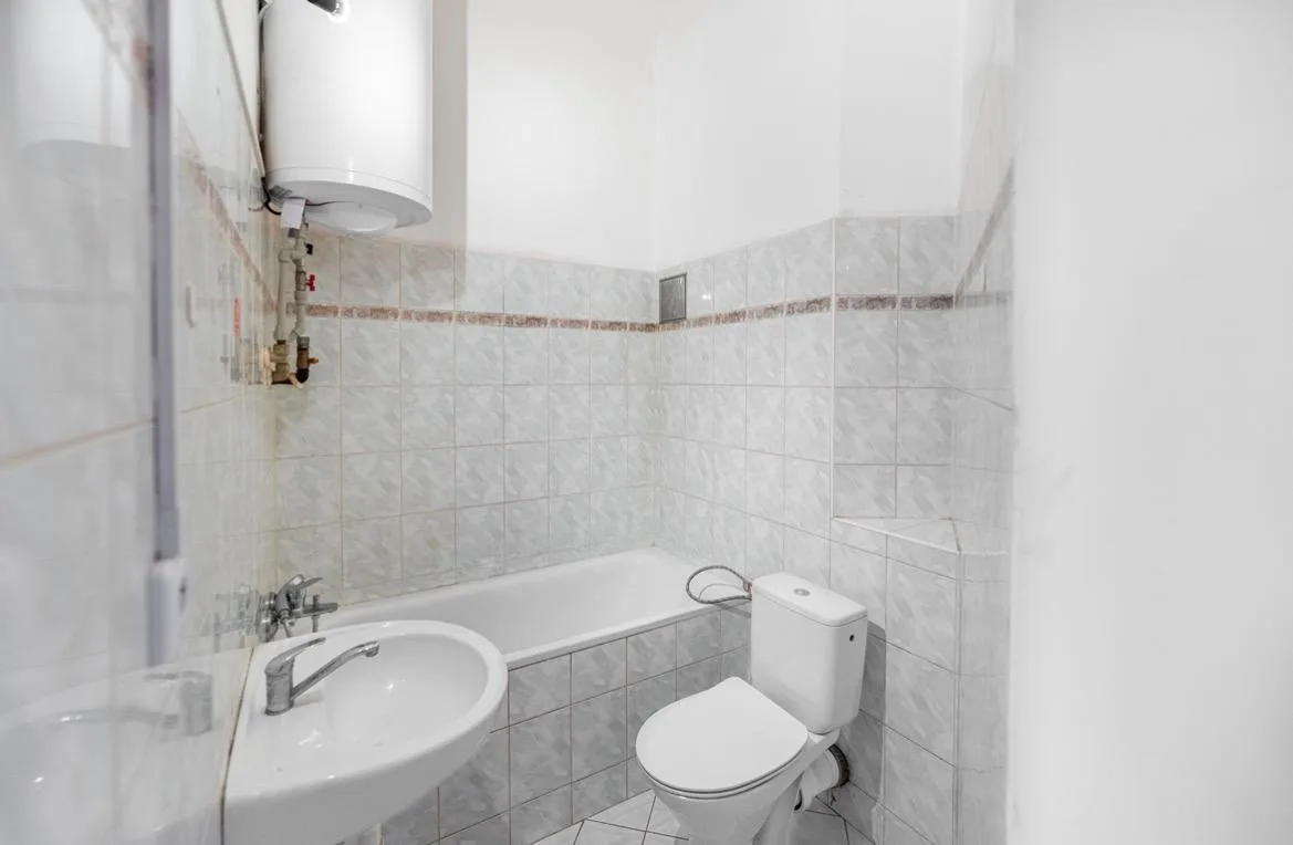Malá koupelna s bílými obklady a vymalovanými horními stěnami a stropem.