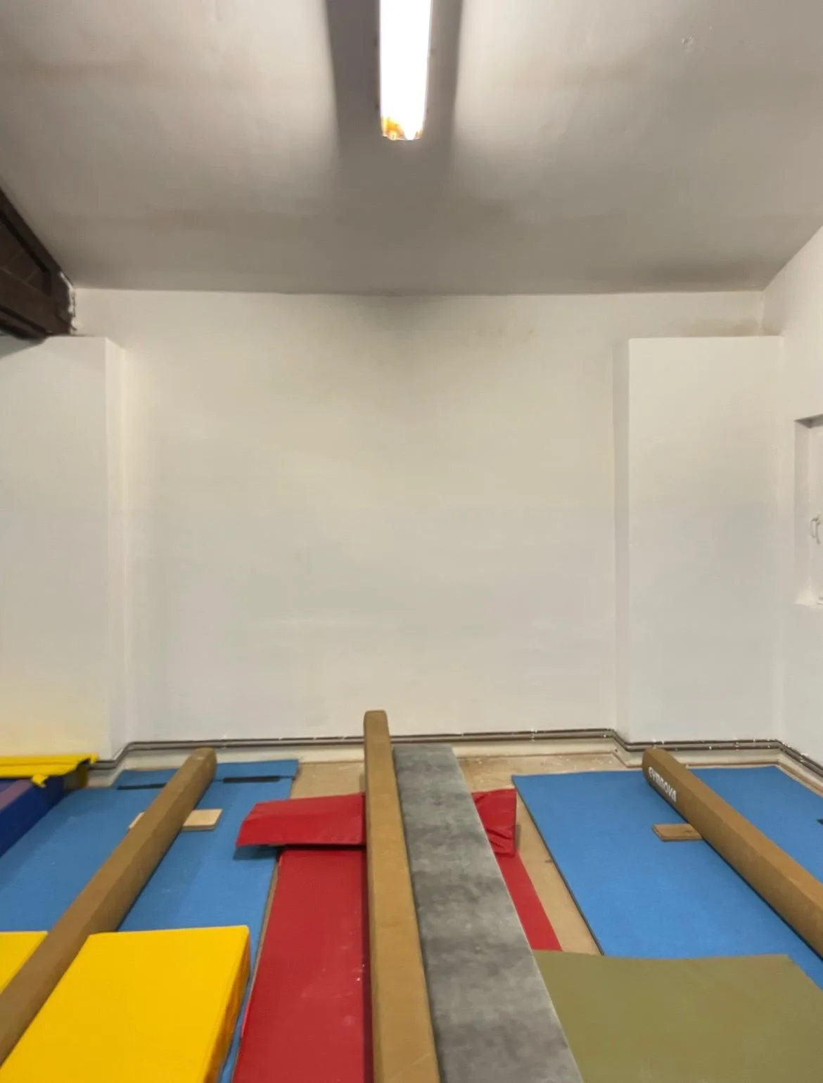 Vymalovana bíla stěna v gymnasticke tělocvičně.